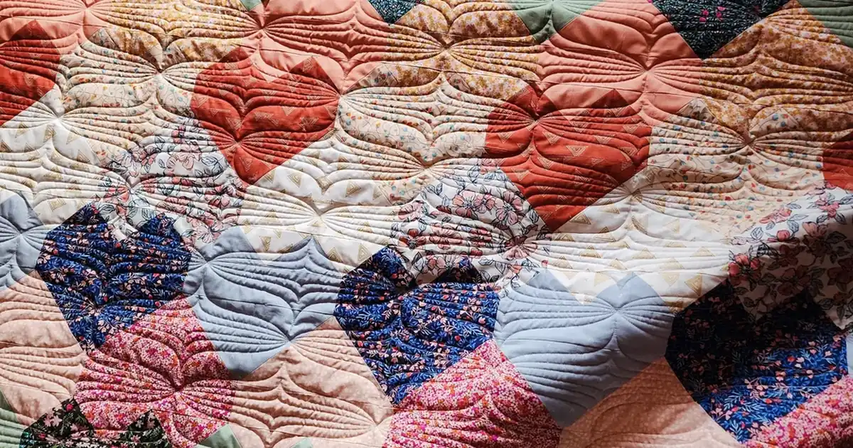 Close-up of a colourful patchwork quilt showing visible hand quilting stitches