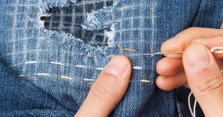 Close-up of hand stitching repairing a tear in fabric with needle and thread