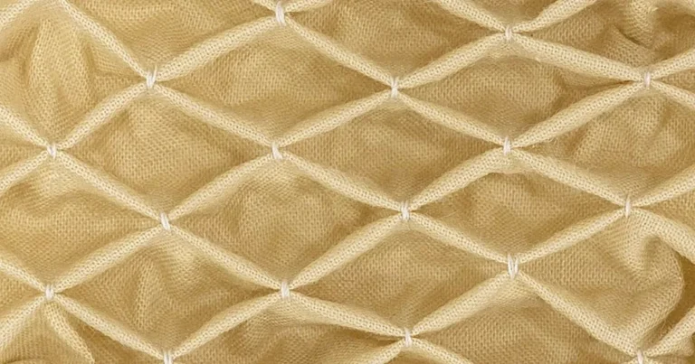 Honeycomb smocking in cream fabric showing the gathered diamond lattice texture