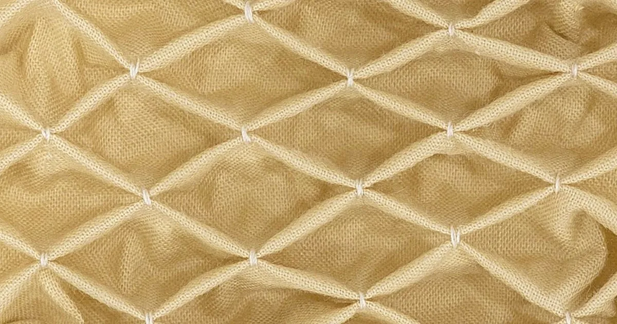 Honeycomb smocking in cream fabric showing the gathered diamond lattice texture