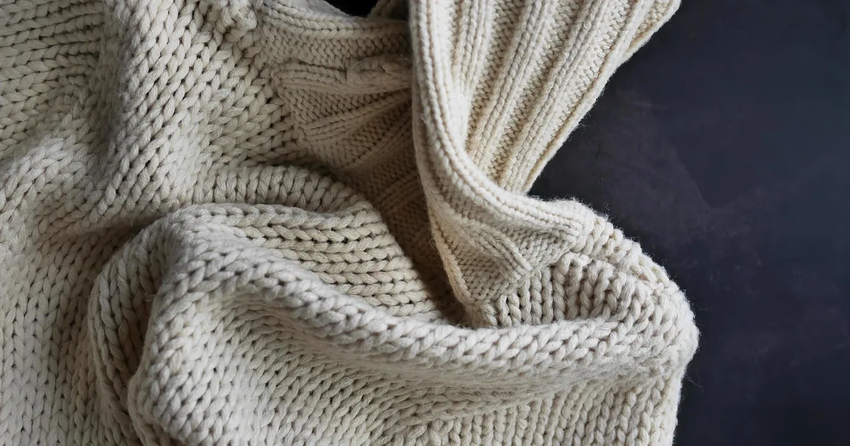 Cream hand-knitted wool sweater texture close-up